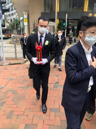 霍启文拿著霍老太的神主牌登上旅游巴。