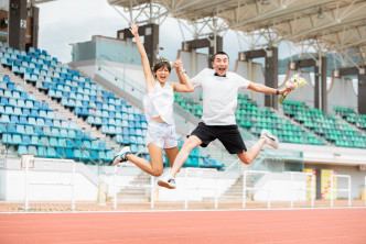 二人以背心T恤、 短裤加波鞋在运动场上飞跃而起。