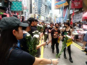 工作人员向途经的游行人士派发白色鲜花。