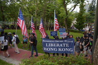 游行队伍中，有人高举美国国旗。