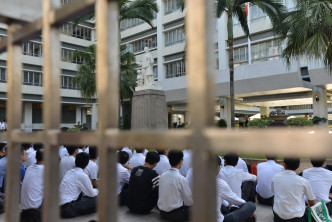 学生在校门的喇沙像前静坐。