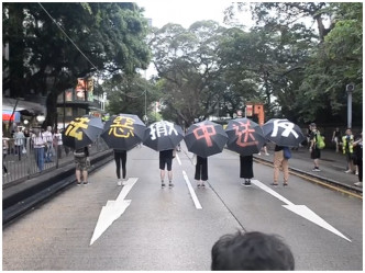 有示威者举伞，展示标语。