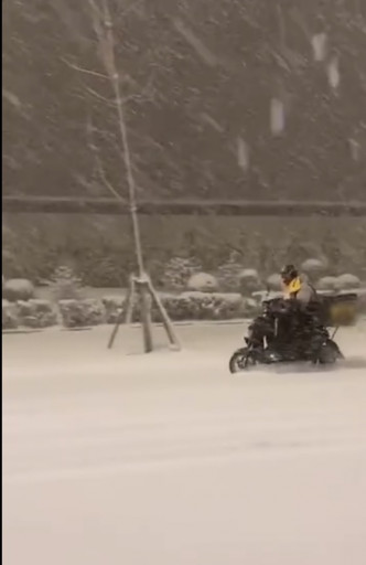 外卖哥驾著电单车冒著大雪前行。网图