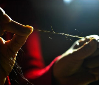 妇人在展示整理编织头发的方法。