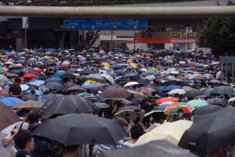 现场不时下骤雨，示威者手持雨伞，坚持留守现场。