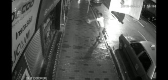 根据商场闭路电视片段可见，一名身穿白衣的青年向店铺淋油。