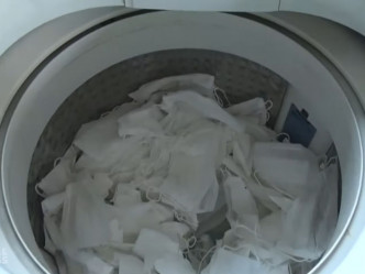 工人将用过的口罩放入洗衣机清洗。(网图)