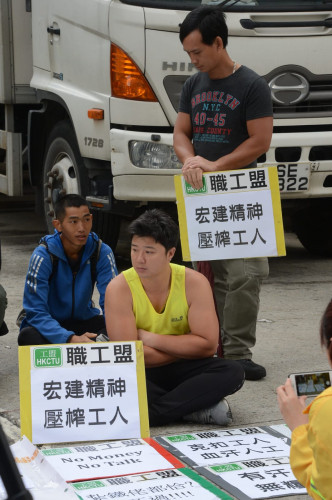 多名紮鐵工在地盤入口靜坐抗議。