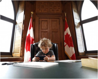 杜鲁多幼子贾斯汀坐在父亲办公室桌上的照片等。网图