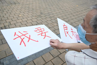 一名男子在维园外举起写有「我要良知」的标语牌被截查。