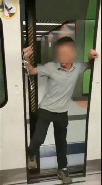 該男子將身體擋住月台幕門和港鐵列車車門。FB群組「On9仔女同盟會」影片截圖