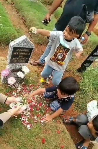 兩人學家人將花瓣灑在墓碑上悼念。影片截圖