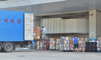工人将物品搬上货车载走。