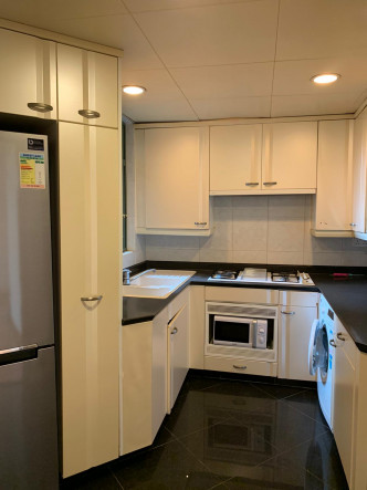 廚房設有多組白色廚櫃，顯得潔淨外亦提供充裕的收納空間。