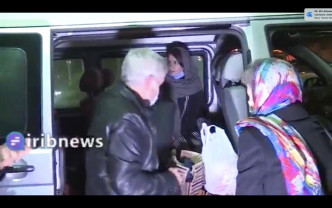 披上灰色头巾获释的女学者穆尔吉尔伯特上一辆汽车离开。AP图片