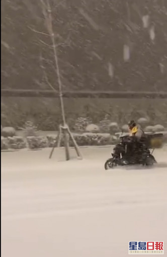 外卖哥驾著电单车冒著大雪前行。网图