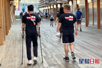 石伟雄（左）左脚受伤，要扶着拐杖走路。  梁柏琛摄