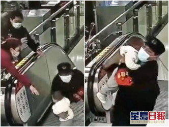职员抱起男童，避免因摔下扶手电梯而造成严重伤害。网图