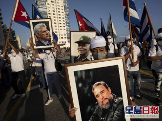 有民眾手持黨旗、橫額，及印有已故革命英雄肖像的標語牌。AP圖片