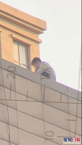 該男子危坐在棟大廈天台，期間撒下多張人民幣鈔票。網圖