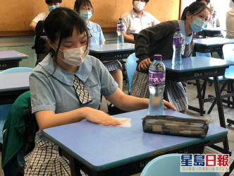 有學生進入課室後，用濕紙巾清潔桌椅及用品。