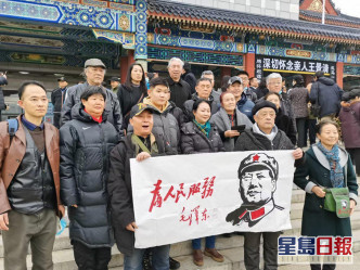 有民众展示毛泽东「为人民服务」的横幅。