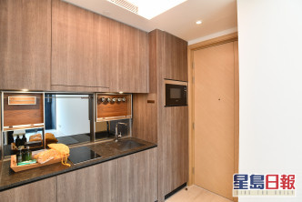 開放式廚房位於客廳一隅，設有廚櫃、微波爐等所需配備。