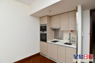 開放式廚房置於廳堂一隅，設有多組廚櫃，收納空間足。