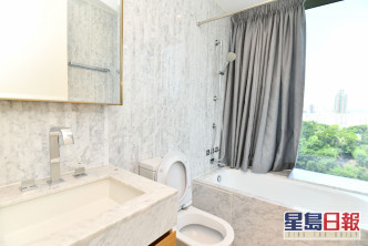 套廁牆身鋪有淺灰色雲石，浴缸旁設大窗，讓住戶浸浴時可欣賞翠綠樹景。
