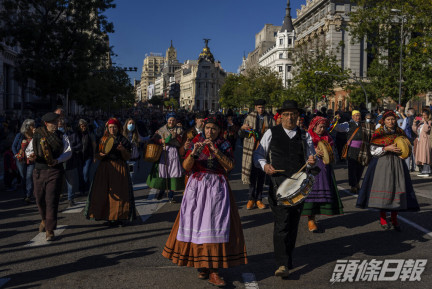 西班牙民眾穿着傳統服裝上街表演。 （美聯社）