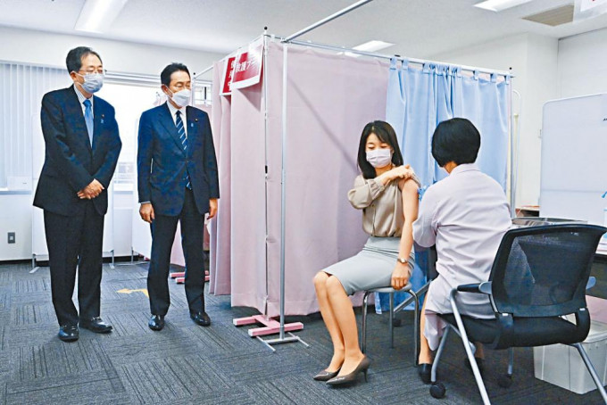 日本首相岸田文雄（左二）在東京羽田機場觀看機場職員接種疫苗。