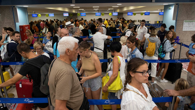 7 月 24 日，希臘羅德島發生山火後，遊客們在機場登機手續辦理櫃檯排隊等待起飛的飛機。路透社