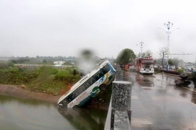 旅游巴车头冲入水中，车尾卡在桥上，有人被困车内，情况十分危急。（网图）