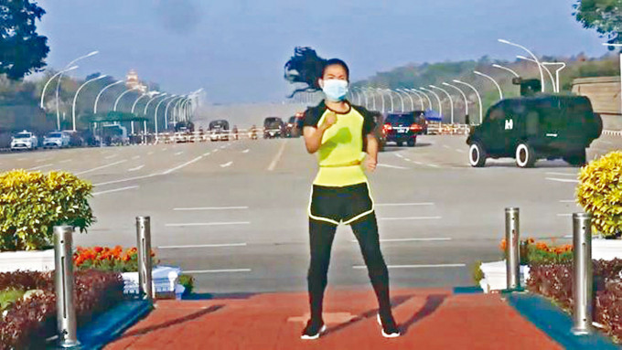 體育老師Khing Hnin Wai跳建美操之際，身後有軍方汽車駛向國會。