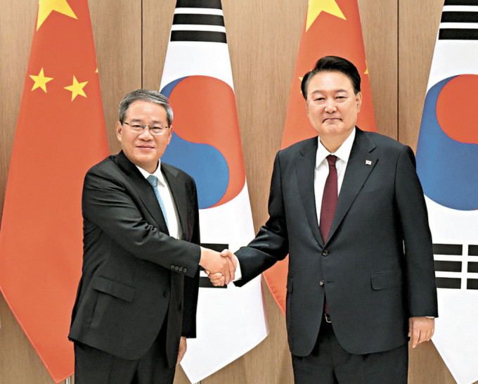 李强与韩国总统尹锡悦握手。