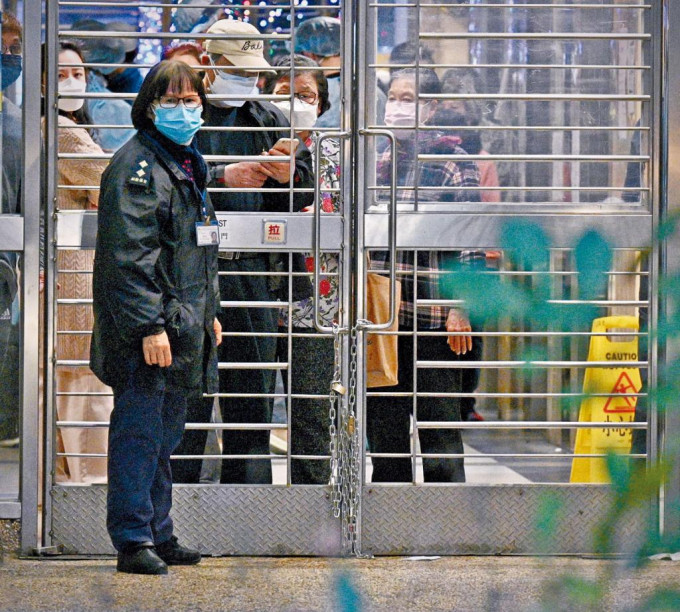 政府宣布封逸葵樓五天後,保安人員隨即用鐵鏈鎖上大閘,不少居民站在門後,大感無奈。
