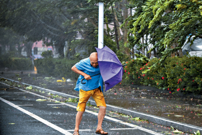 台风为海南带来狂风暴雨，市民撑伞外出需与强风对抗。