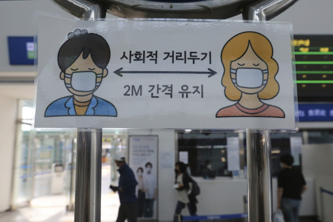 南韓宣傳載口罩及保持社交距離的橫額。AP圖