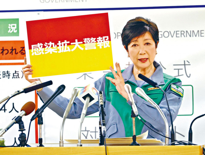 東京都知事小池百合子周三在記者會上，展示「感染擴大」警告牌。