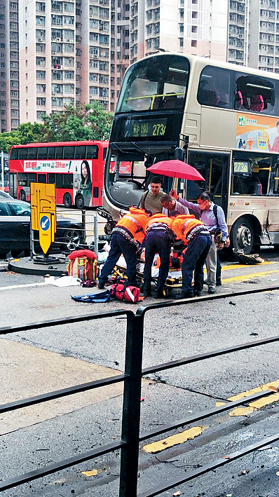 意外後救護員為傷者施救，有熱心途人打傘遮雨。