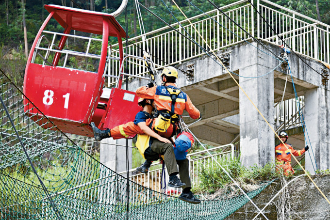 「山岳高空繩索T形救援」模擬山谷內建築物廢墟有人員被困，包括模擬救援人員救出被困纜車市民。