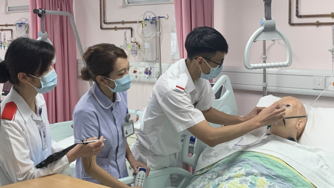 朱慧玲(左)指導袁海鑌(右)為模擬人偶戴上氧氣罩，黃子晴(中)負責調整病床角度。