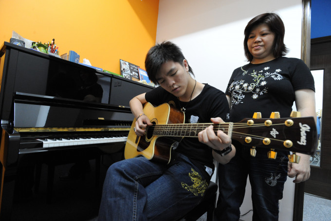 义务音乐导师「Wilson哥哥」戎景豪（左）在母亲从旁协助下，为有特殊需要（SEN）学童进行遥距教学。 林家希摄