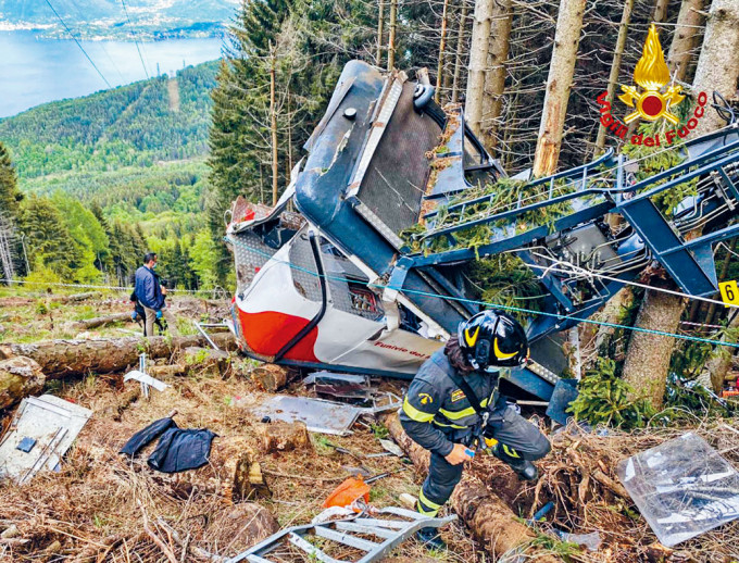 ■救援人员在坠毁缆车车厢旁搜救。