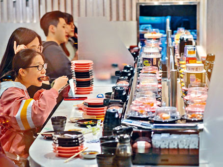 ■廻转寿司的送食物带重开，食客忘情大啖品尝美食。