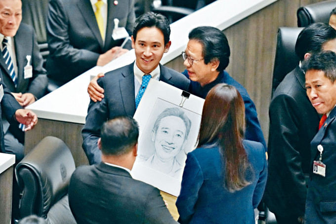 前進黨黨魁皮塔（左）昨日被憲法法庭暫停眾議員職務，他離開議事廳前，展示為泰黨議員贈送他的肖像。