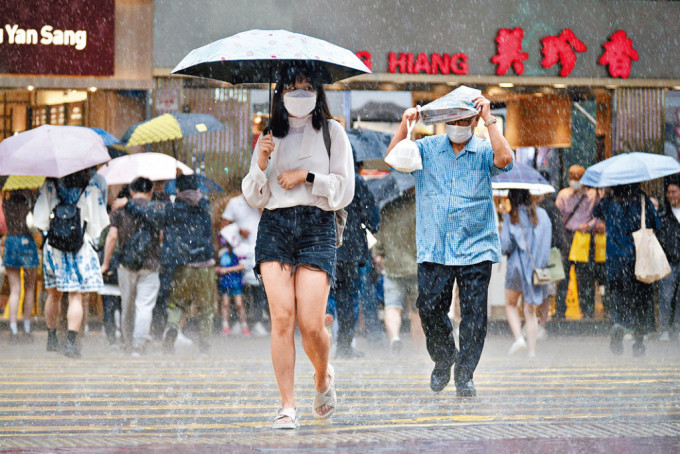 全港多区下大雨，有市民临急以报纸挡雨。