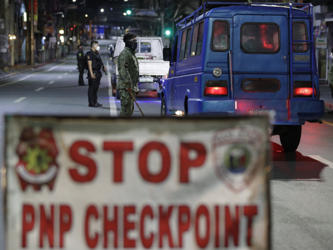 馬尼拉宵禁實施後，多名警察到大馬尼拉地區的檢查站，檢查司機的證件。AP圖片