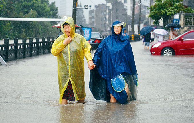 颱風「黑格比」登陸，兩名溫州居民在積水中前行。　