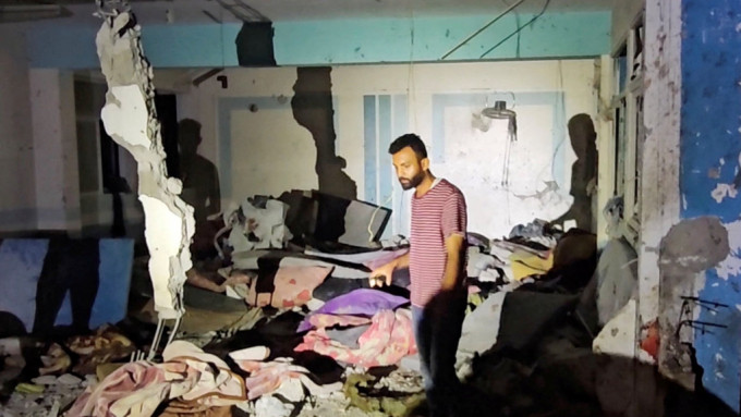 一名男子检视以军空袭击中的UNRWA学校残骸。 路透社